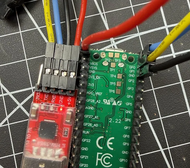 Close-up of four jumper wires between the USB-to-TTL adapter and the Pico