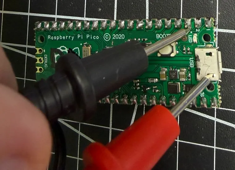 Multimeter probes touching pins on the Pico